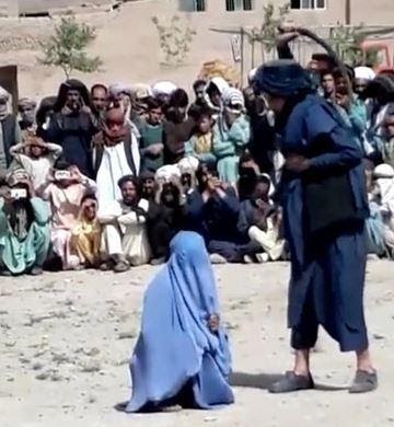 Taliban fighters whip an unnamed woman after she spoke to a man on the phone in 2016